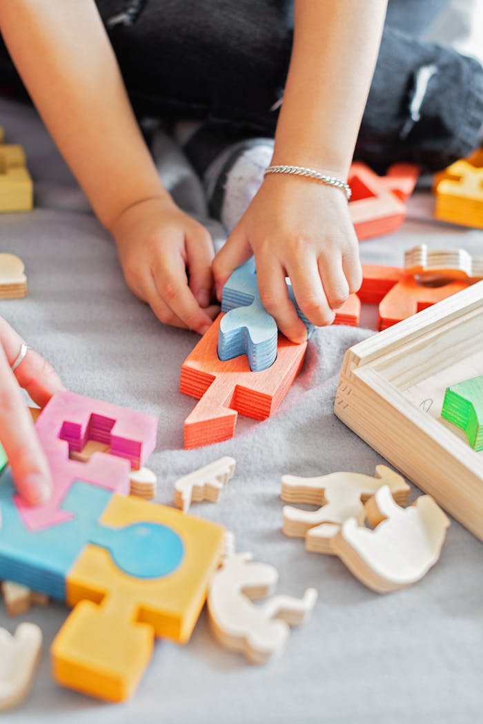 Close-up of children's hands assembling colorful wooden puzzle pieces indoors.