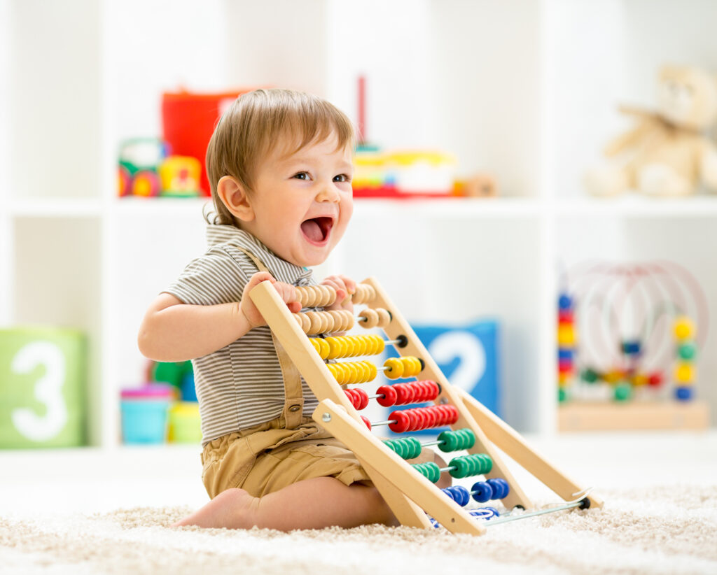 Little child boy playing with toy blocks. Baby in nursery or kin